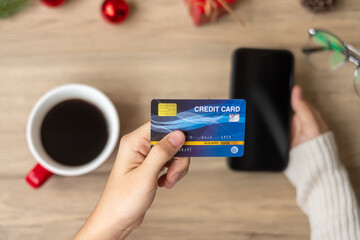 Hand holding credit card for online shopping on smartphone during drinking coffee. Merry Christmas eve, December, seasonal, Black Friday sale, New Year and holiday concept