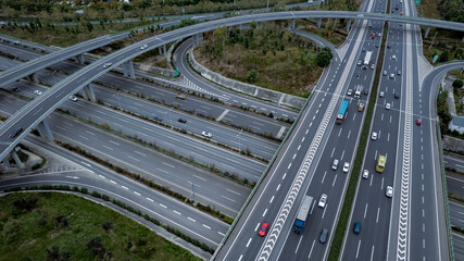 Top down aerial view from drone on modern traffic junction of multiple lane highway road in metropolis city. Heavy traffic on motorways. Elevated curved roads, clover shape bridge with no speed limit.