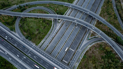 Top down aerial view from drone on modern traffic junction of multiple lane highway road in metropolis city. Heavy traffic on motorways. Elevated curved roads, clover shape bridge with no speed limit.