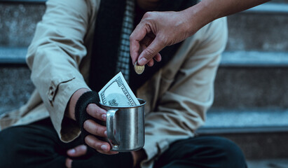 Woman giving money to homeless beggar man sitting in city.Giving concept.