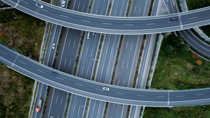 Top down aerial view from drone on modern traffic junction of multiple lane highway road in metropolis city. Heavy traffic on motorways. Elevated curved roads, clover shape bridge with no speed limit.