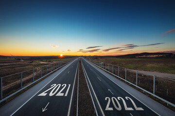 Driving on open road at beautiful sunny day from old 2021 to new year 2022. Aerial landscape view