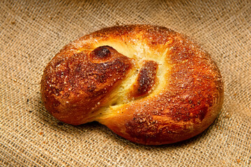 Sweet bun with a golden crust on the background of the fabric.