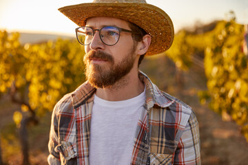 Stylish young bearded man looking away pensively in countryside