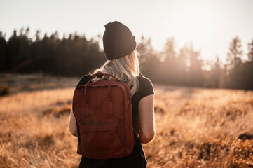  Young traveler hiking girl with backpacks. Hiking in nature. Sunset mood. Sunny landscape. Tourist...