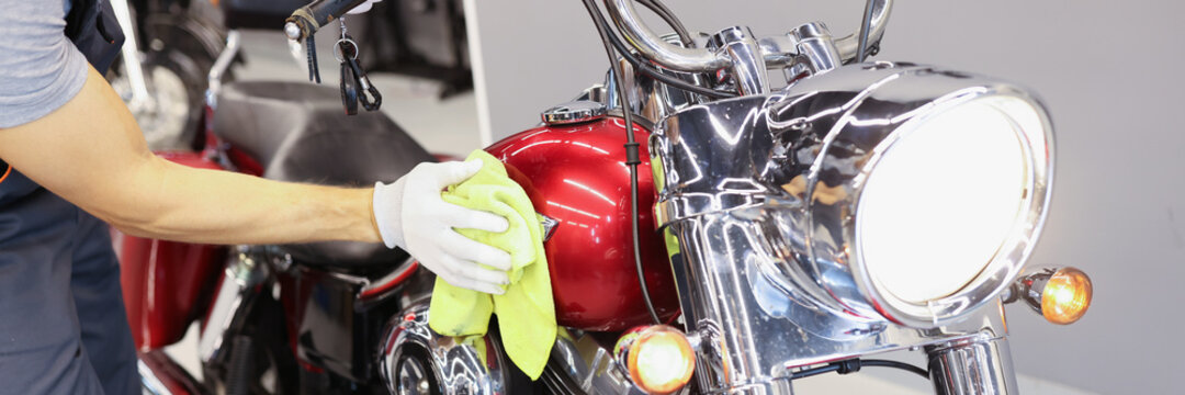 Man cleaning motorcycle in service center closeup