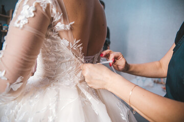 Obraz na płótnie Canvas The bride's fees. The bride's dress is fastened on the back