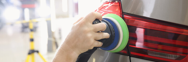 Hands with orbital polisher in auto repair shop closeup