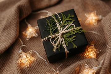 Christmas gift packed in black wrapping paper lying on soft woolen background