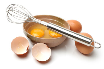Wire whisk and brown eggs on white background 
