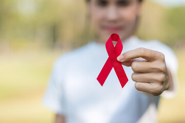 Hand holding Red Ribbon for supporting people living and illness. Healthcare and safe sex concept. December World Aids Day and multiple myeloma Cancer Awareness month