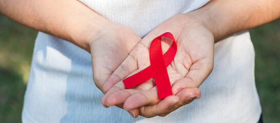 Hand holding Red Ribbon for supporting people living and illness. Healthcare and safe sex concept....