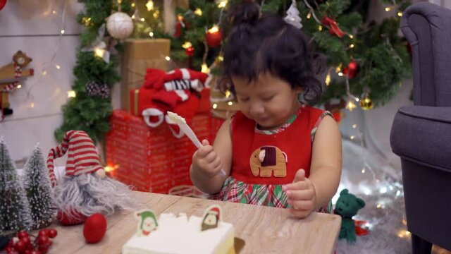 Happy Asian little girl with Christmas cake at home on winter holiday with family.