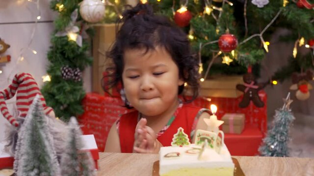 Happy Asian little girl with Christmas cake at home on winter holiday with family.