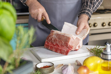 Staying at home and cooking. Man in the kitchen cuts meat, prepares food.