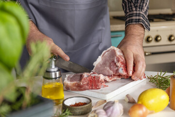 Staying at home and cooking. Man in the kitchen cuts meat, prepares food.