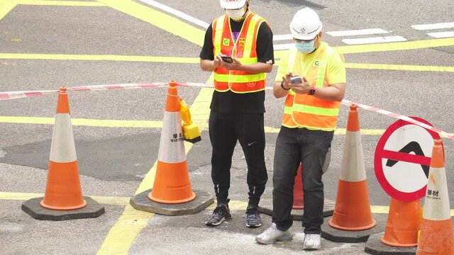 Road workers discuss the plan. next to traffic cones on a road construction site in Hong Kong