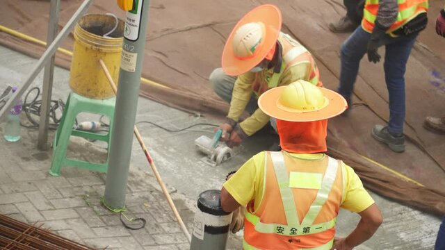 Construction worker  squatting to use a wet saw to cut through concrete in the road