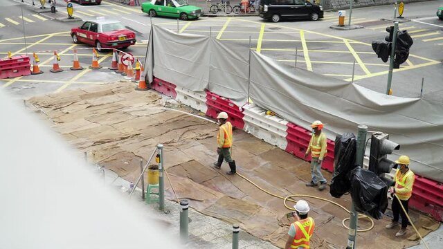 Construction workes wetting the surface. Road contruction site at an intersection a in Hong Kong
