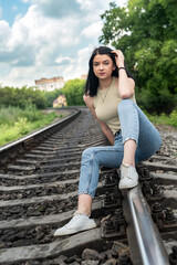 pretty young woman is standing near the railway tracks