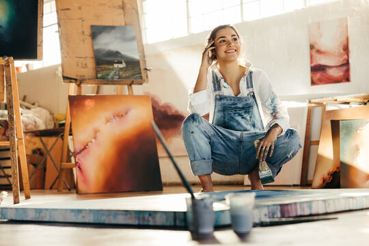 Thoughtful young artist smiling in her studio