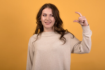 A beautiful and confused Caucasian brunette girl with wavy hair in a casual jumper showing her...
