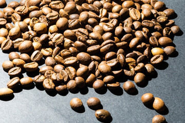 Pile coffee beans isolated on black background and texture, top view.