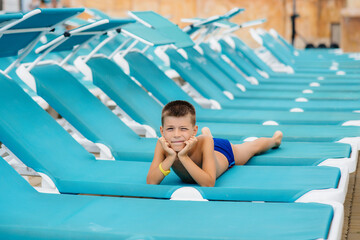 A little boy is smiling happily and sunbathing on a sun lounger on a sunny day. Happy vacation...