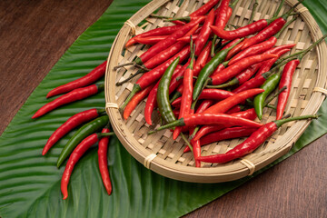 Red and green Chili pepper in basket on banana leaf background.