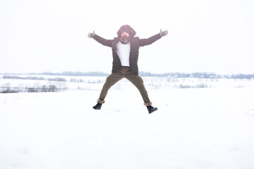 Outdoor portrait of handsome man in coat and scurf. Bearded man in the winter woods.