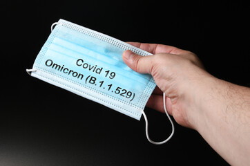 man hold an antiviral medical mask for protection against coronavirus with text Covid 19 Omicron...