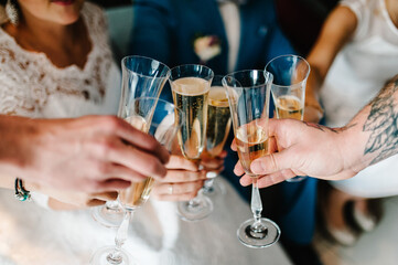 Cheers! People celebrate and raise glasses of wine for toast. Group of men and women cheering with champagne. Close up.