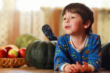 Fototapeta premium Little child choose a pumpkin at autumn. Child sitting on giant pumpkin. Pumpkin is traditional vegetable used on American holidays - Halloween and Thanksgiving Day.