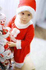 Merry bright christmas. Lovely baby enjoy christmas. Childhood memories. Santa girl little child celebrate christmas at home. Family holiday. Girl cute child cheerful mood play near christmas tree.