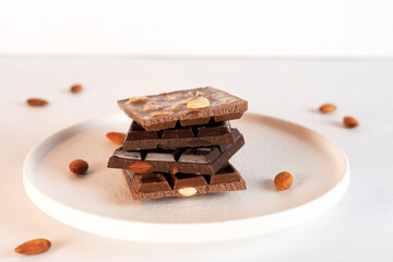 Natural organic pieces of chocolate bars with nuts on white background. Confectionery ingredients. Side view.