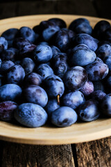 Plate ripe plums in light from window.