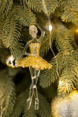 Close up of holidays location with gold glass ballerina toy and garlands on green Christmas tree