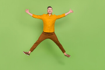 Full body photo of mature excited man have fun jump up energetic isolated over green color background