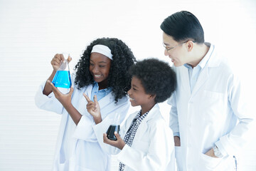 Little African kids studying chemistry and doing chemical science experiment in laboratory at school with Asian teacher man. Excited dark skinned boy and girl looking at liquid color in test bottle