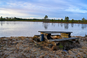 sunset over small lake and resting area with bench and table