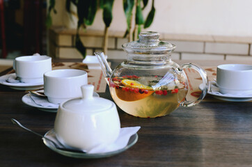 Top view of glass teapot and cups of tea on a table at restaurant close up. Tea ceremony. Holiday concept. Hot winter drinks. 