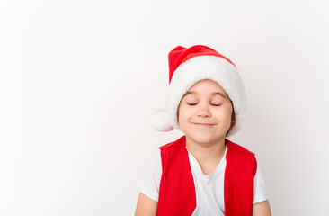 Portrait of cute happy smiling child in red Santa Claus hat isolated on white background. Beautiful five-year European boy. Merry Christmas mockup design. New Year elf. Closed eyes. In anticipating