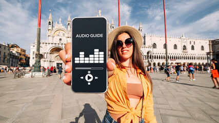 Audio tour online app on digital mobile smartphone. Happy young student woman holding phone...