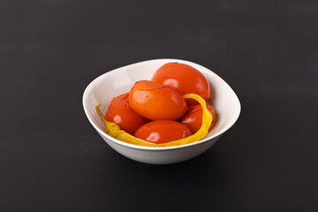 Pickled red tomatoes with chilli in a plate.