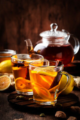 Hot black winter tea with ginger, honey, lemon and spice. Immune booster drink in glass cup on rustic wooden table background, copy space