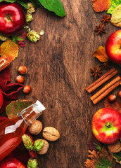 Apple cider bottle with cinnamon sticks, cloves and anise on wooden background. Traditional autumn, winter drink and cocktail, top view