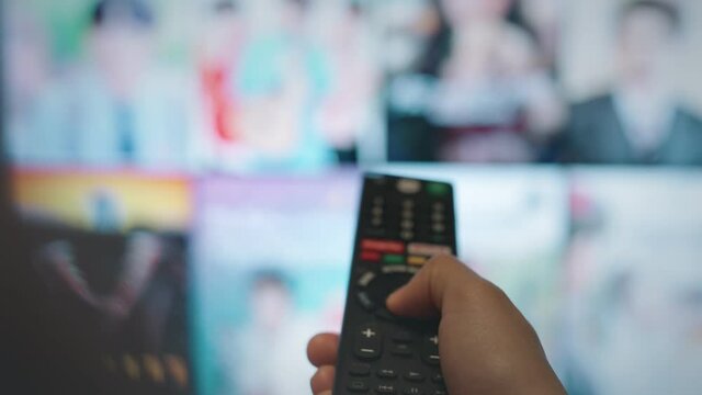 Online video streaming service, Hand holding remote control to select online movies on smart tv.