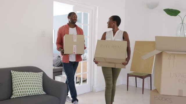 Mid adult black couple holding cardboard boxes relocating in new home