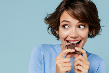 Close up young happy woman in casual sweater hold sweet pink cream donuts biting chocolate bar look...