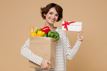 Young fun cheerful vegetarian woman 20s in casual clothes hold paper bag with vegetables hold gift...